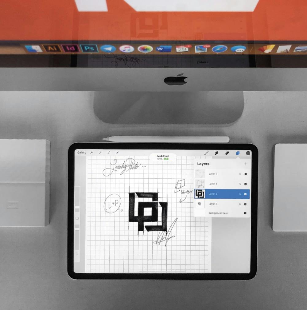 Tablet with a drawing of the logo, iMac computer out of focus.